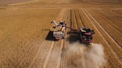 A wheat harvester and support truck harvesting a field of wheat. Credit: Adobe stock.